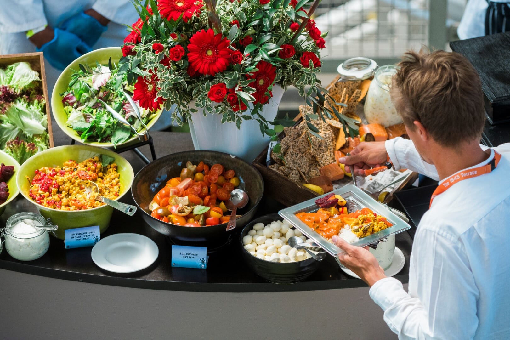 A person holding a plate of delicious food and selecting from a luxurious range of dishes at a Gala Event.